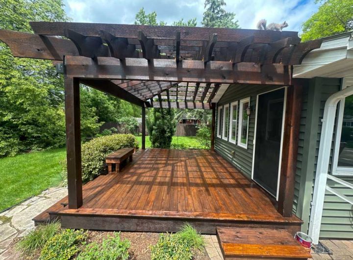 Rustic wooden pergola over a spacious deck, complemented by lush garden surroundings, creating a natural and serene outdoor dining area.