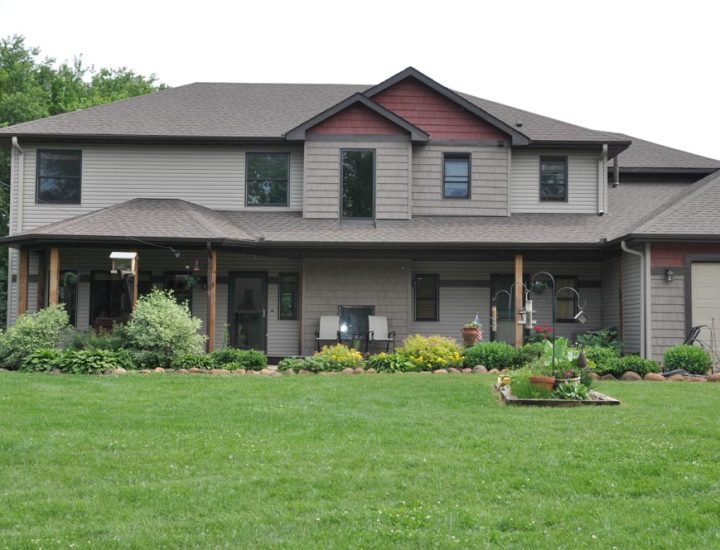 A front view of the house with wide front yard, enhanced exterior and roofing